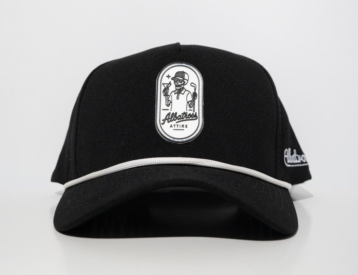 A black baseball cap with a white embroidered patch on the front featuring a skeleton wearing a top hat and the text 'Allstars ATTIRE'. The cap also has a white piping detail along the edge of the brim and a white embroidered logo on the side.